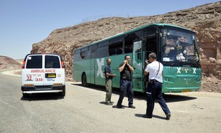 Israeli emergency personnel stand near a bus north of Red Sea resort of Eilat