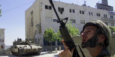 A ISRAELI SOLDIER SECURES THE AREA AS PALESTINIAN MEN LEAVE THE CHURCHIN BETHLEHEM.