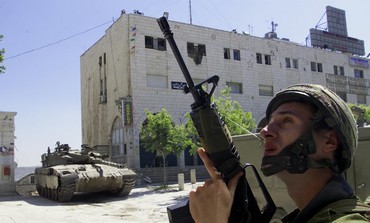 A ISRAELI SOLDIER SECURES THE AREA AS PALESTINIAN MEN LEAVE THE CHURCHIN BETHLEHEM.